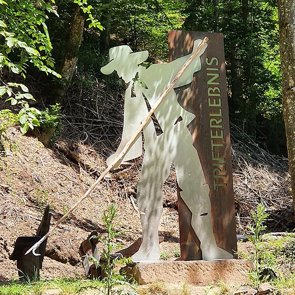 Metallfigur des Triftkönigs Johann, im Hintergrund Bäume